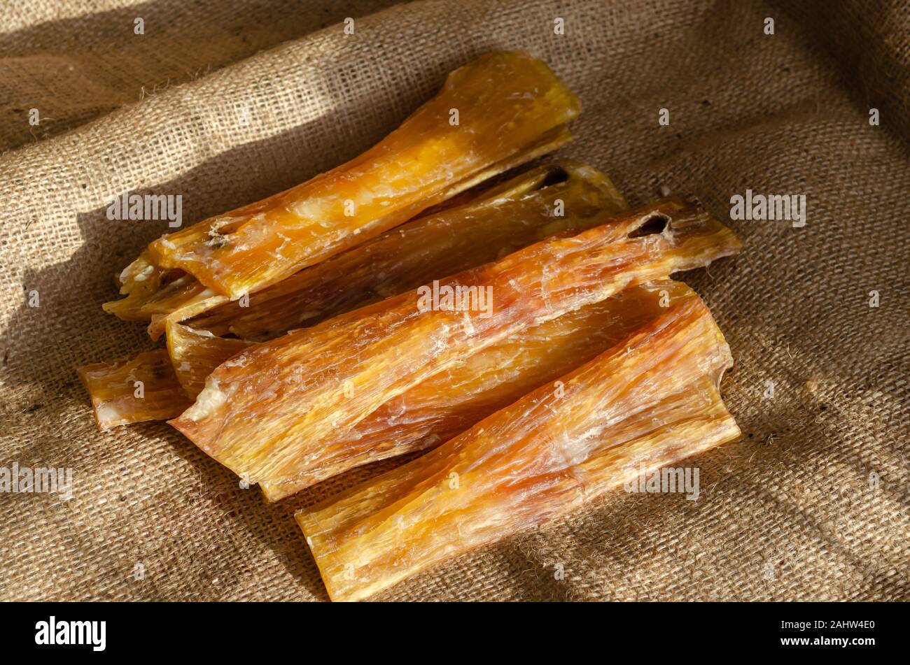 Naturale chicche da masticare per cani. Carni bovine essiccate tendine su tela. Chicche dentale per animali domestici di tutte le razze e di età. Messa a fuoco selettiva. Close-up. Foto Stock