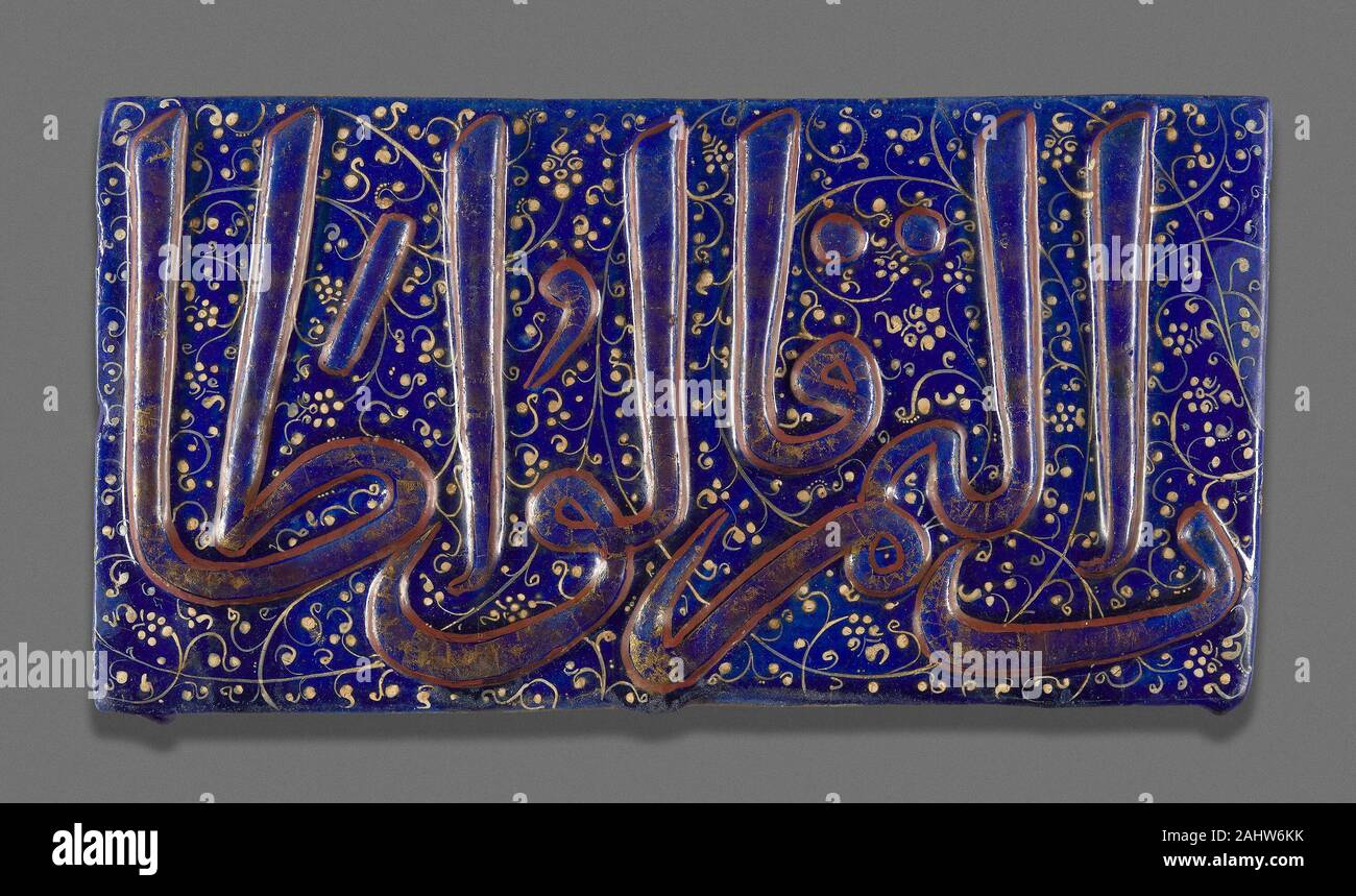 Islamico. Piastrella. 1301-1353. L'Iran. Fritware, stampato e decorate con foglie di doratura e rosso su uno smalto blu (lajvardina) Overglaze ceramica dipinta su uno sfondo blu, chiamato lajvardina, sono stati sviluppati da ilkhanide potters nel XIV secolo in Iran. Mercanzia Lajvardina sono noti per motivi geometrici, sebbene la calligrafia può anche essere presente soprattutto su piastrelle. Tali piastrelle non sono sopravvissute in grande quantità perché la foglia oro e pittura overglaze hanno sofferto di esposizione agli elementi.Nonostante la diminuzione della sua foglia oro decorazione, questa mattonella illustra il sontuoso risultati finali di t Foto Stock