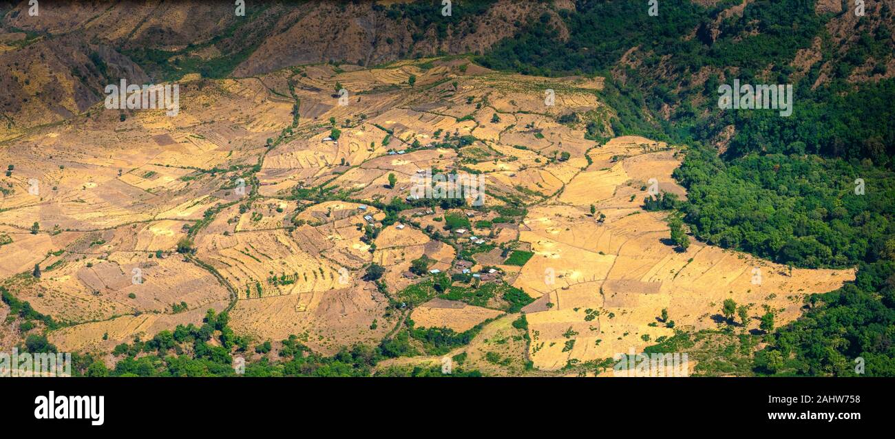 Etiopia, vista dal bordo del Semien Montagne in una valle con il villaggio Adarmas, circondato da campi di raccolto Foto Stock