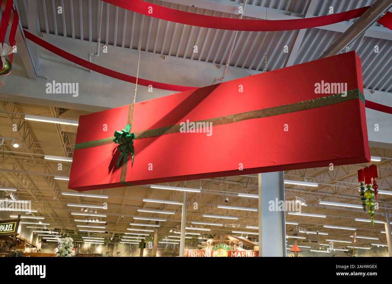 Rossa gigante regalo di Natale scatola è sospesa sopra le navate laterali all'interno di un Bass Pro Shop store a Gainesville, Florida. Foto Stock
