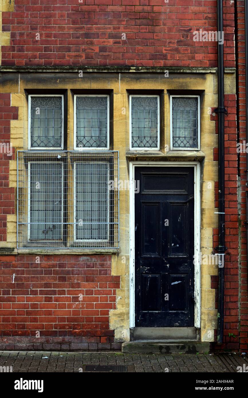 Porta nera su una vecchia casa in mattoni rossi con gated rispetto a Windows Foto Stock