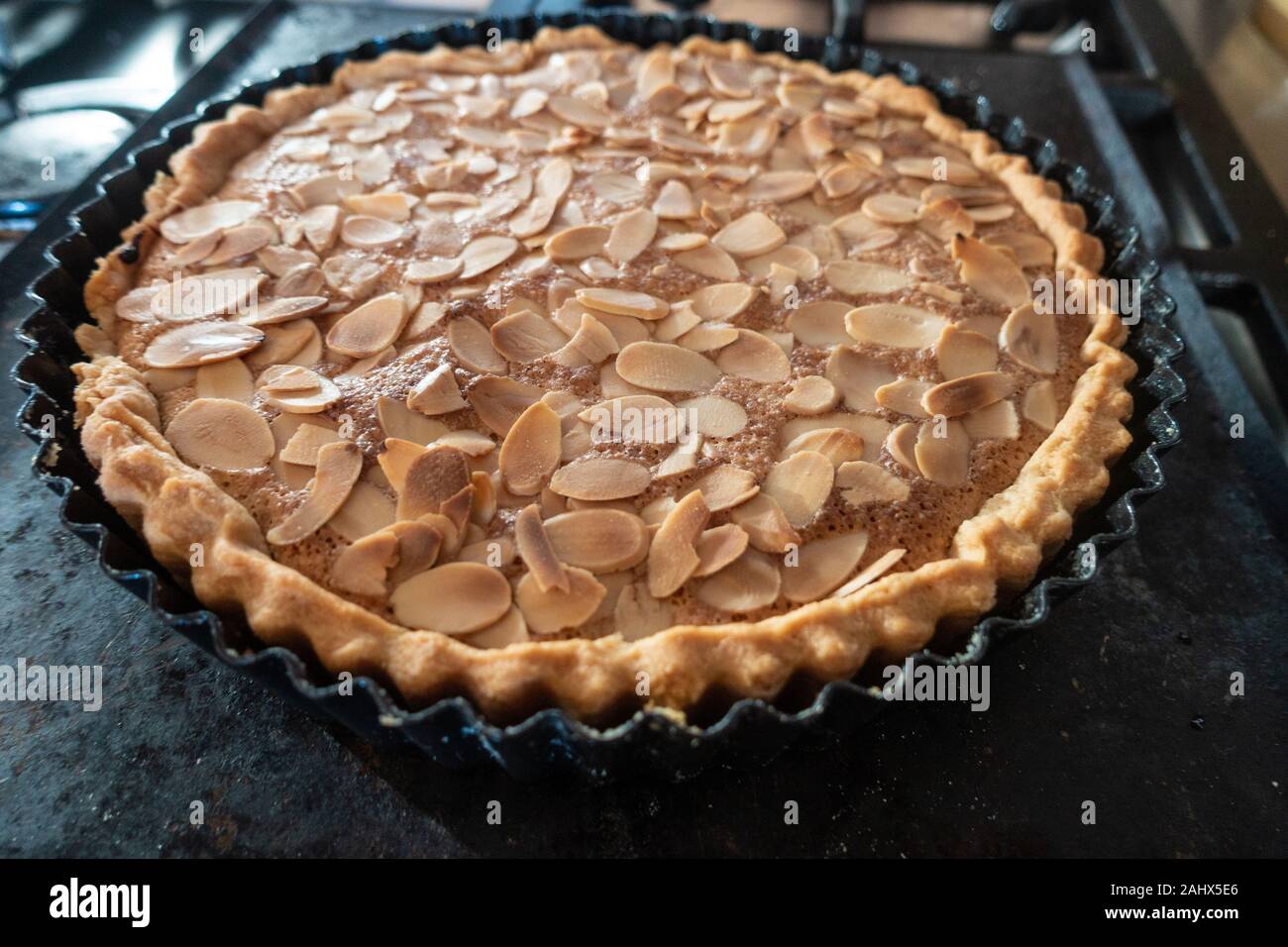 Un fatti in casa, pane appena sfornato, bakewell tart guarnita con mandorle tostate si raffredda in una teglia da forno su una teglia da forno. Foto Stock