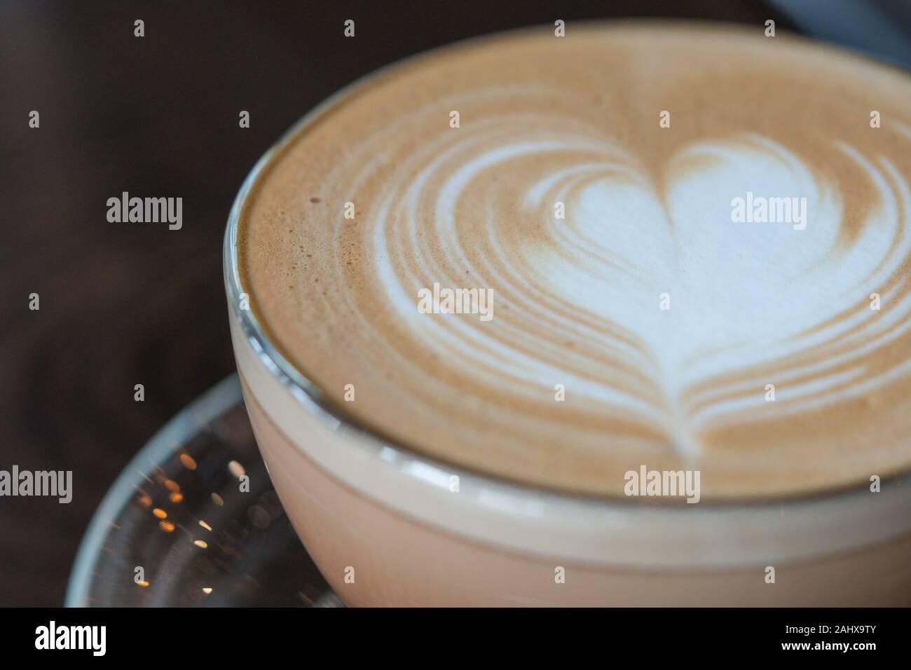 Cappuccino o latte caffè con forma di cuore in un vetro trasparente cup su sfondo di legno Foto Stock