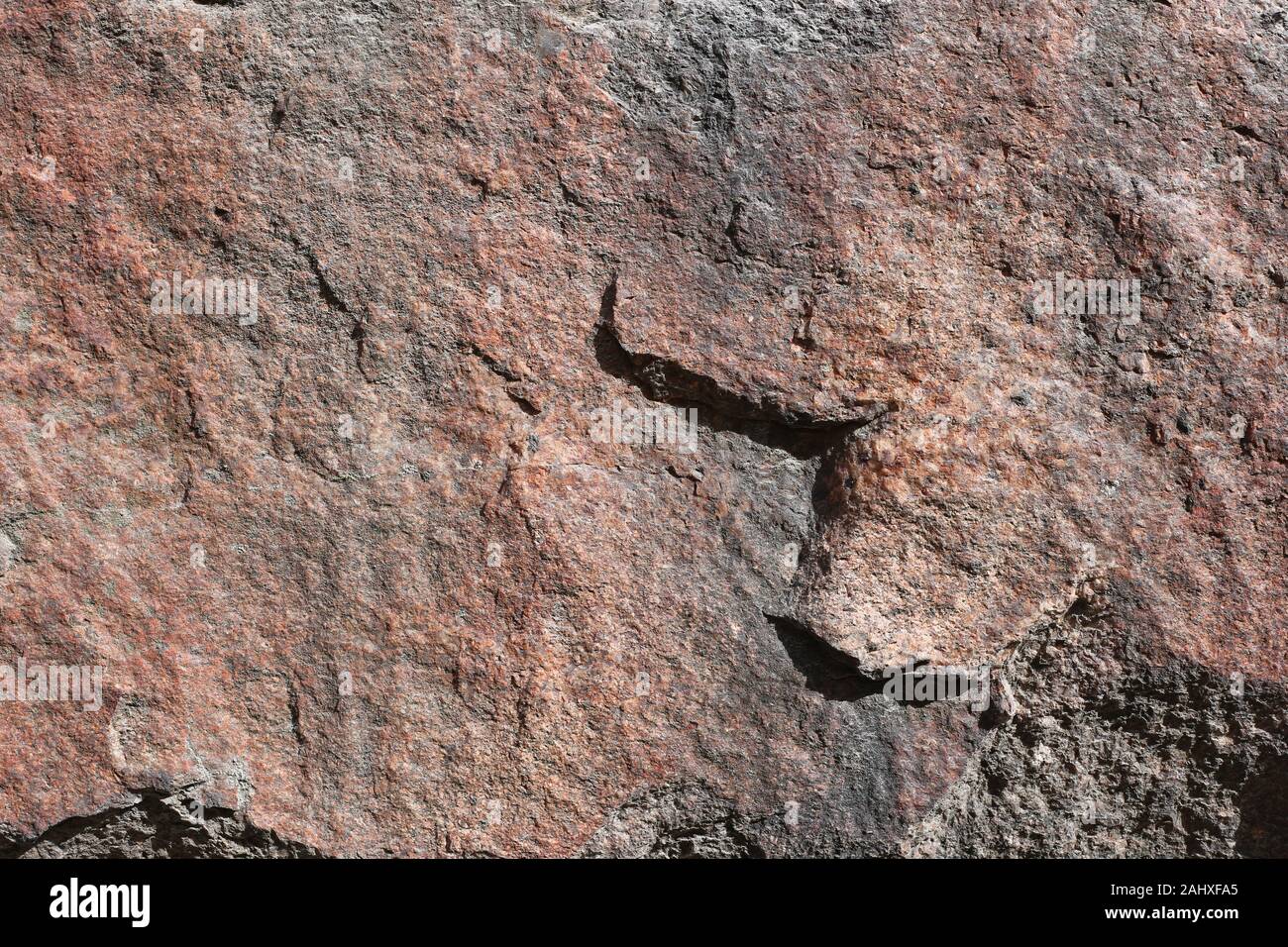 Primo piano di una grossa pietra in rosso, arancio e toni di nero. In questa foto si può vedere la texture rustico di una roccia in dettaglio. La perfetta immagine di sfondo. Foto Stock