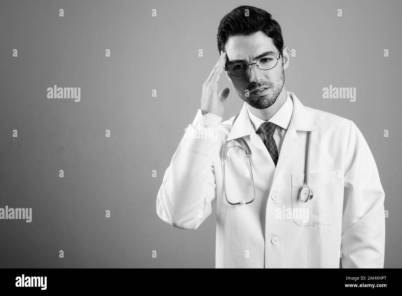 Ritratto di giovane uomo bello medico contro uno sfondo grigio Foto Stock