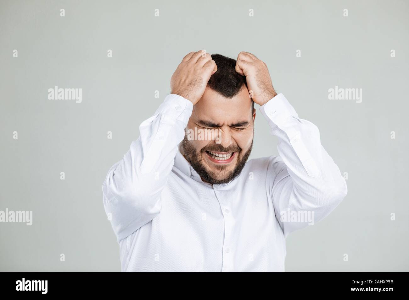 Uomo Barbuto mantiene la mano sulla testa su sfondo grigio. l uomo dimentica qualcosa Foto Stock