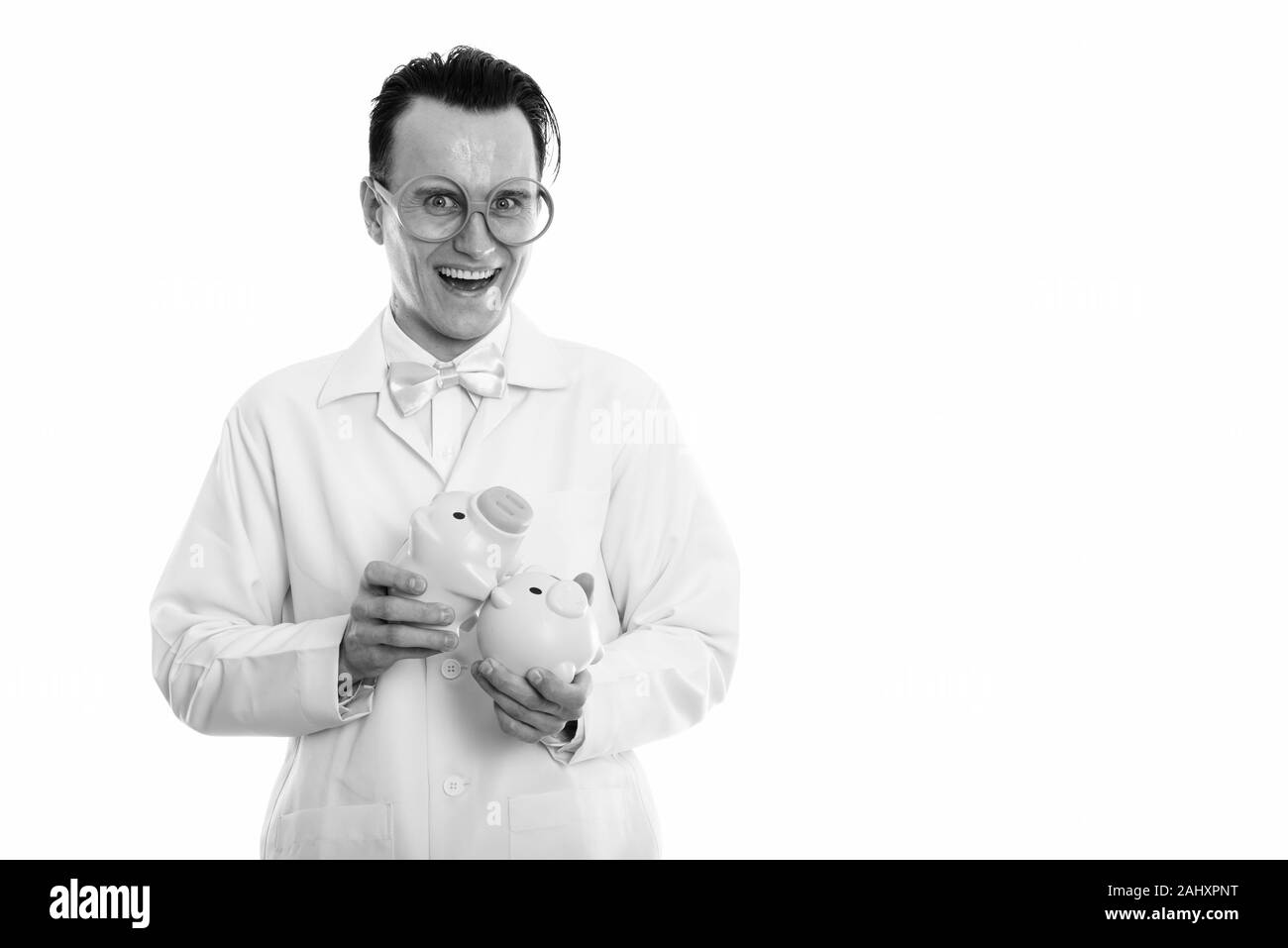 Studio shot di felice pazzo uomo sorridente medico mentre si tiene due piggy banche al di sopra di ogni altro Foto Stock