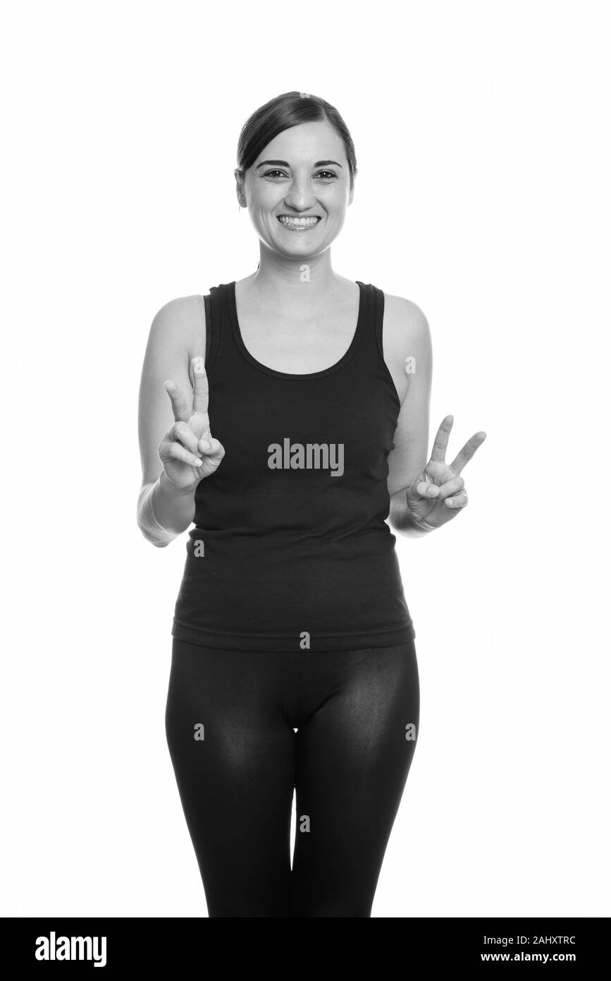 Studio shot di felice bella donna sorridente mentre dà segno di pace con entrambe le mani Foto Stock