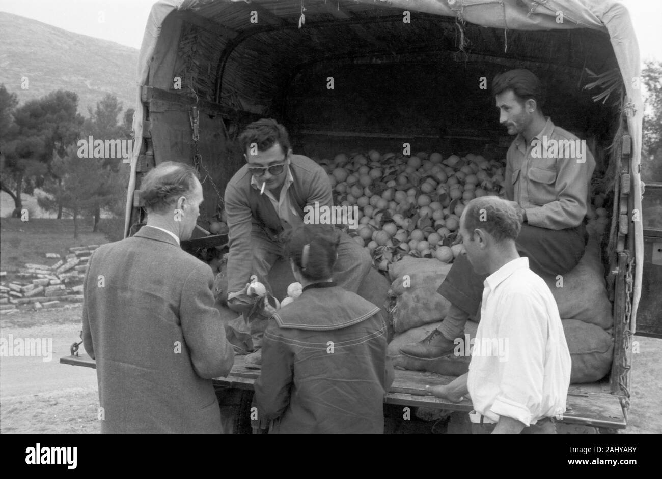 Verkauf von Orangen aus dem LKW un Touristen während einer Tour durch die Ruinen des alten antiken Olympia, Griechenland 1950er. La vendita di arance dal carrello per turisti durante un tour delle rovine dell'antica Olympia, Grecia degli anni cinquanta. Foto Stock