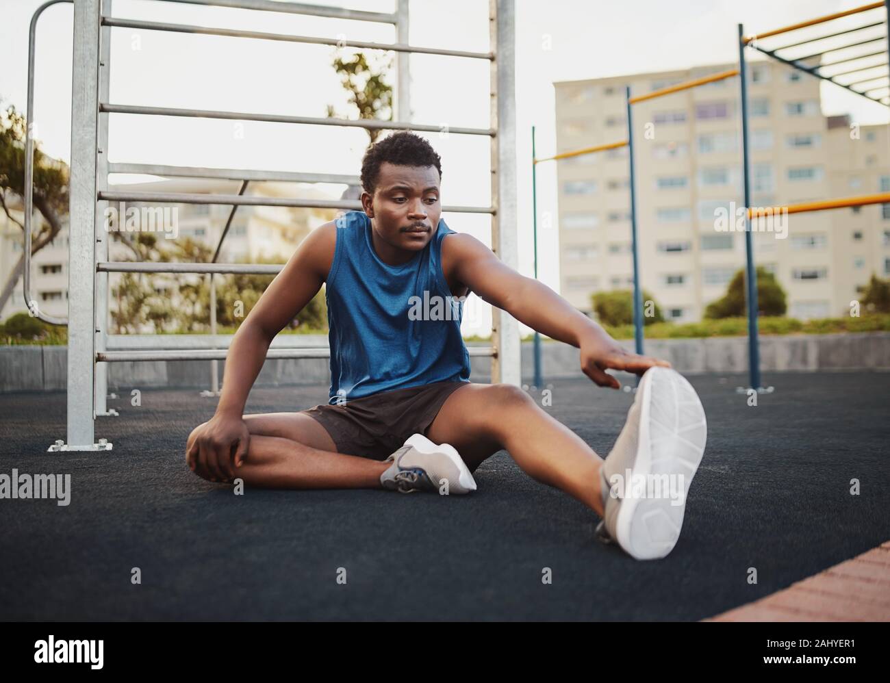 African American giovane uomo fitness che allunga la gamba e il riscaldamento per la formazione presso palestra esterna park Foto Stock