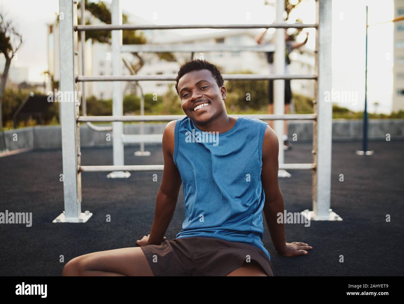 Ritratto di un giovane sorridente americano africano atleta maschio relax dopo un intenso allenamento in palestra esterna park Foto Stock