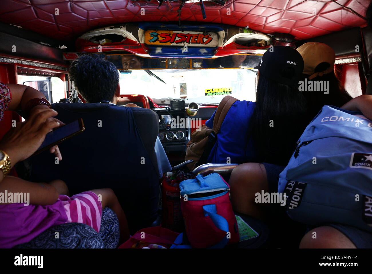 Antipolo City, Filippine - 27 dicembre 2019: il conducente ed i passeggeri all'interno di una jeep di passeggeri che viaggiano in una giornata di sole. Foto Stock