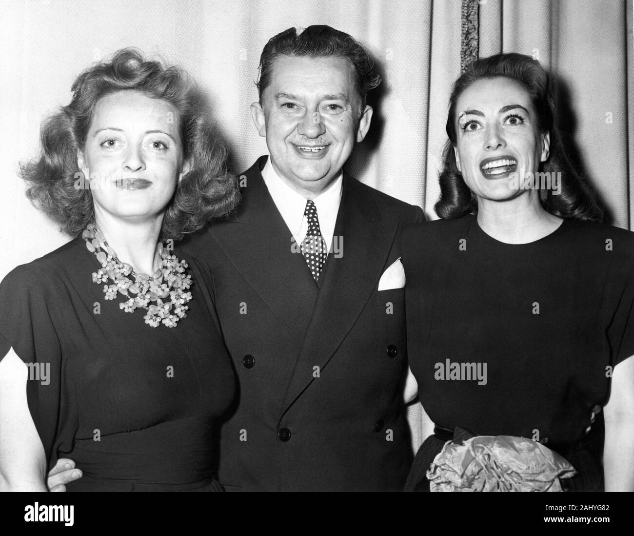 BETTE DAVIS e Joan Crawford con Jean Hersholt attore e Presidente della Accademia delle Arti e delle scienze cinematografiche a un cocktail party presso il Beverly Hills Hotel California in 1944 Foto Stock