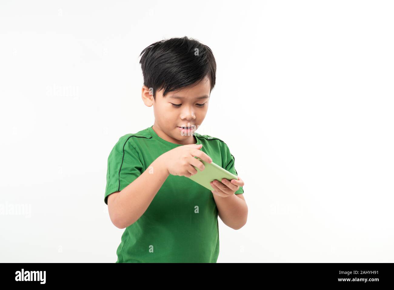 Ritratto di un divertito carino piccolo kid giochi su smartphone isolate su sfondo bianco Foto Stock