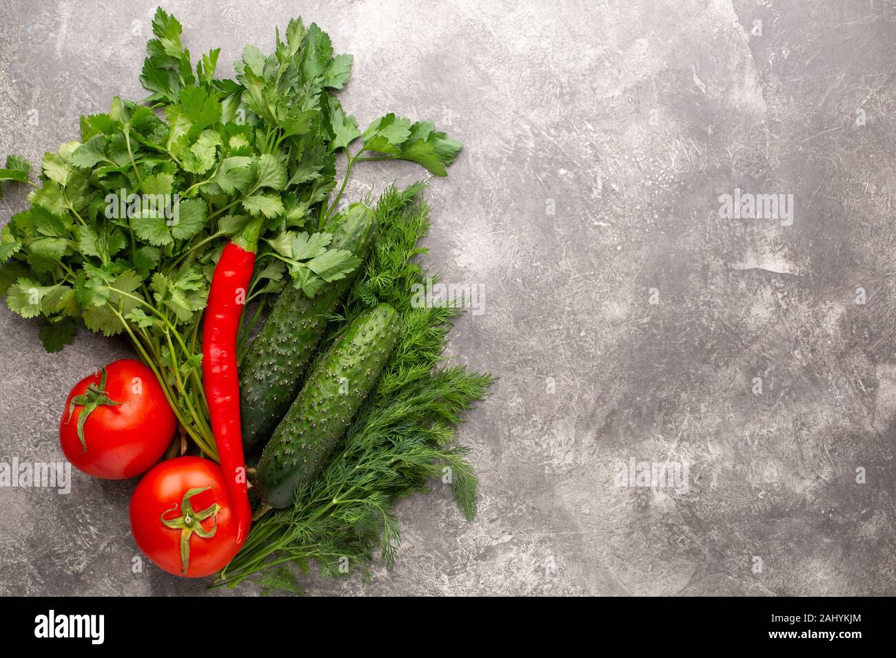 Diverse verdure fresche, pomodori, cetrioli e peperoncino su un cemento grigio Sfondo. Vista dall'alto. Copia dello spazio. Foto Stock