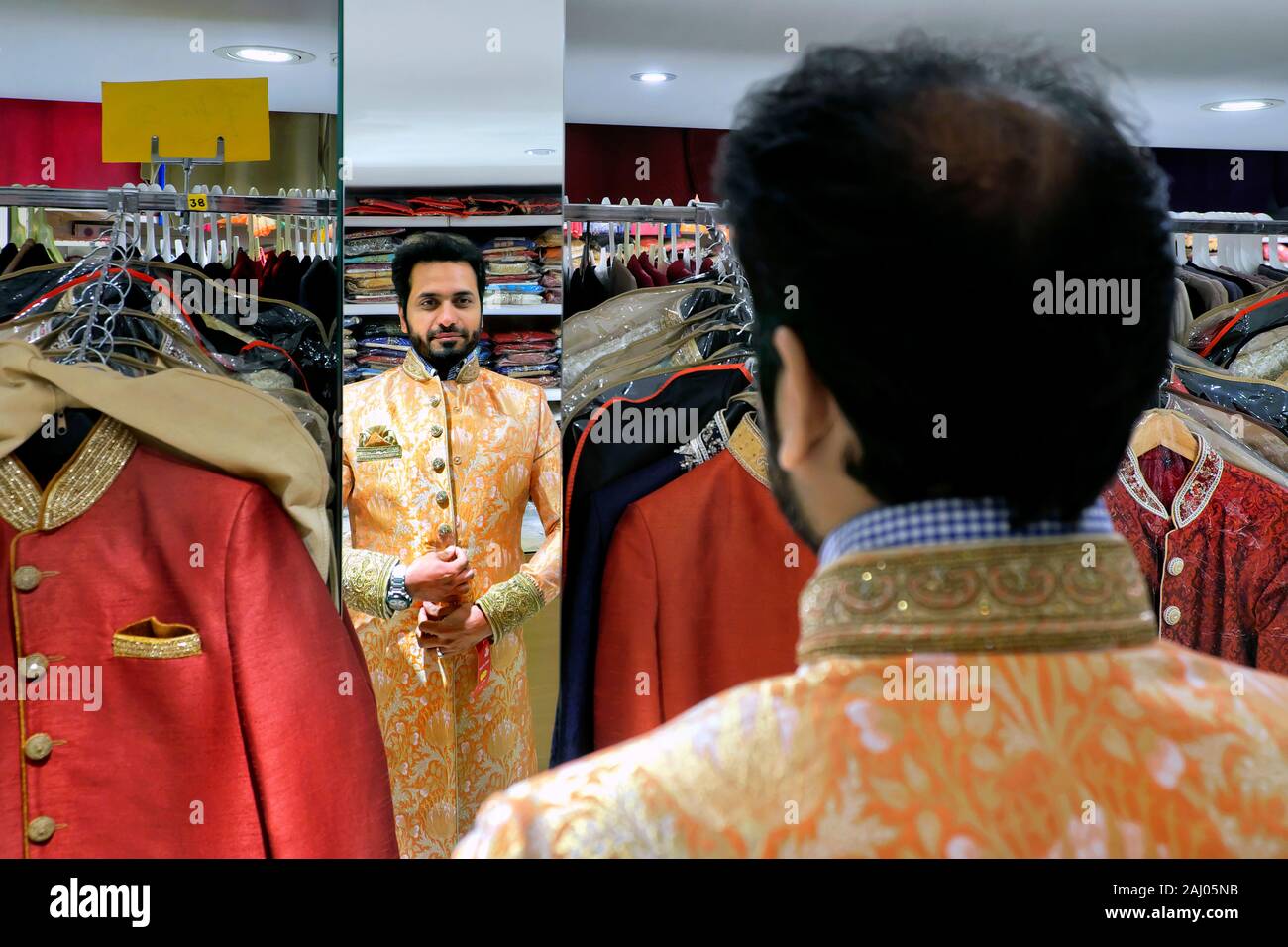 Provando un colorato sherwani suit, Saree Mandir shop, Belgrave Road, Leicester, Leicestershire, England, Regno Unito, Europa Foto Stock