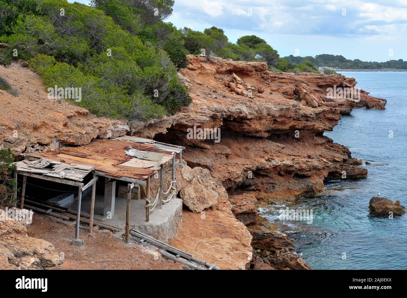 Una vista sopra la Sala Caleta cove nell isola di Ibiza, Spagna, con un tradizionale rifugio di pescatori in primo piano Foto Stock