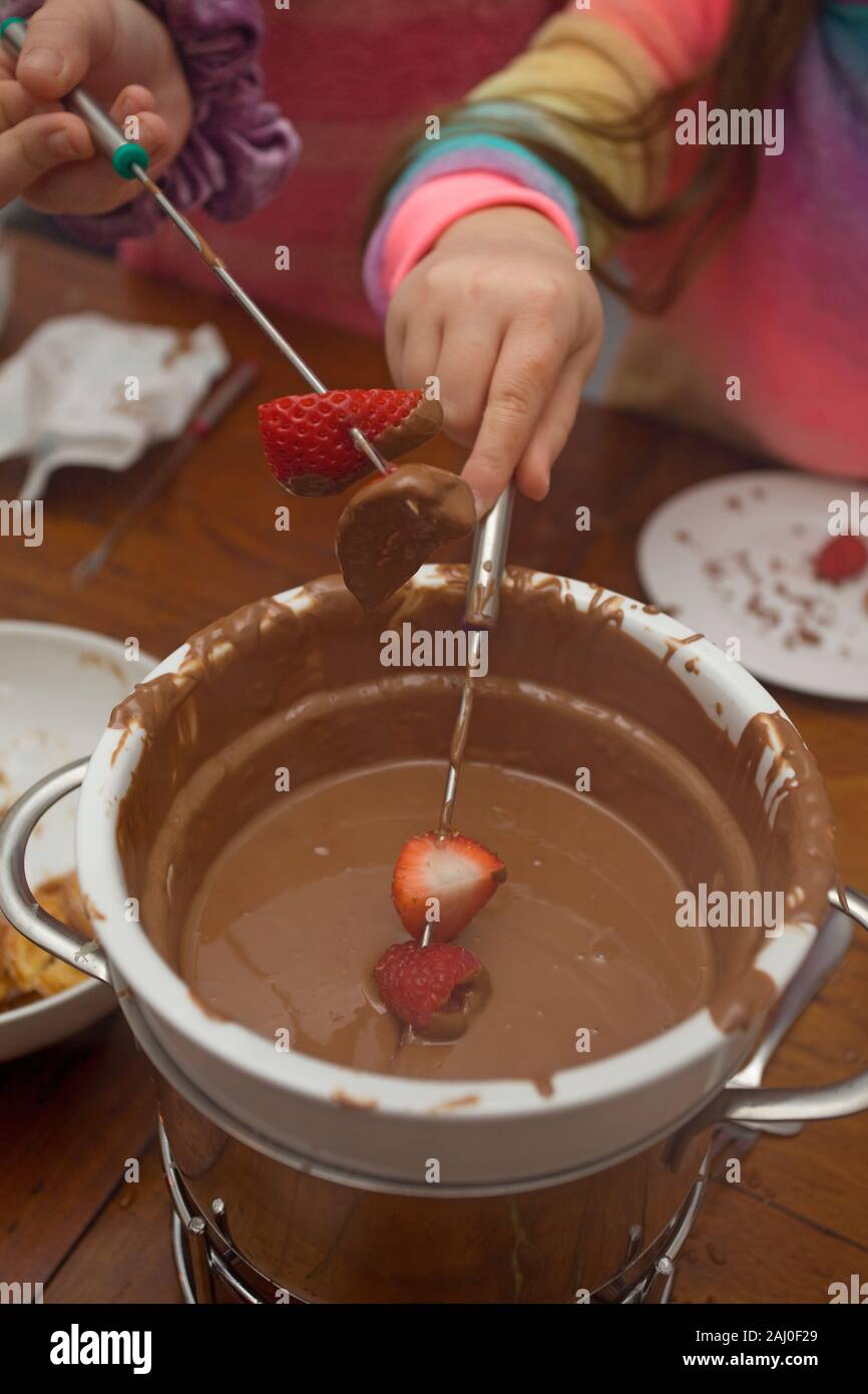 I bambini a mangiare la fonduta di cioccolato Foto Stock