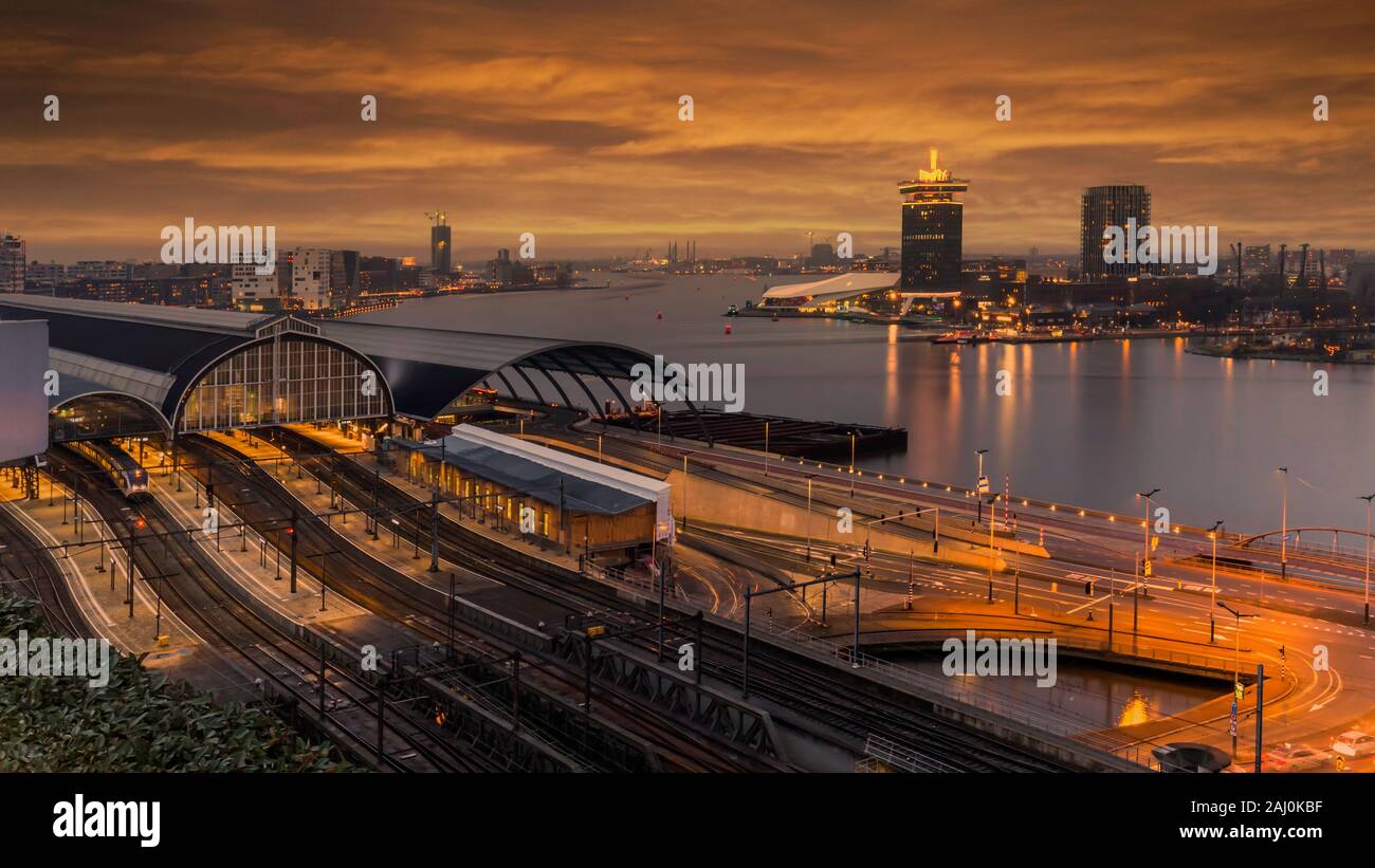 Vista del Amsterdam stazione ferroviaria e il fiume Amstel di notte, Paesi Bassi Foto Stock