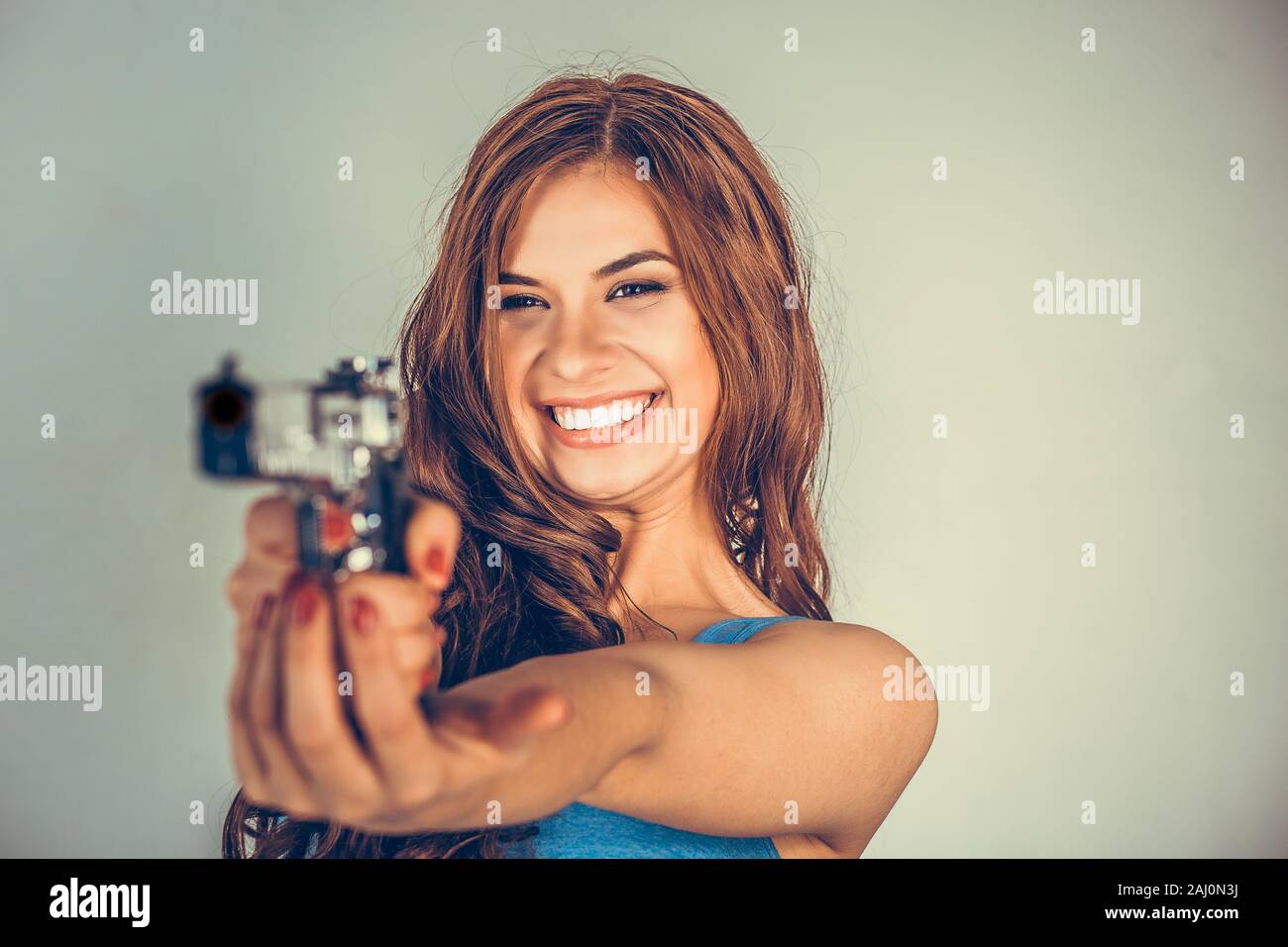 Bella giovane donna con una pistola. Brunette holding pistola alla ricerca finalizzata, puntando alla fotocamera.violento gangster ribelle bandit self-nozione di giustizia. Mixe Foto Stock