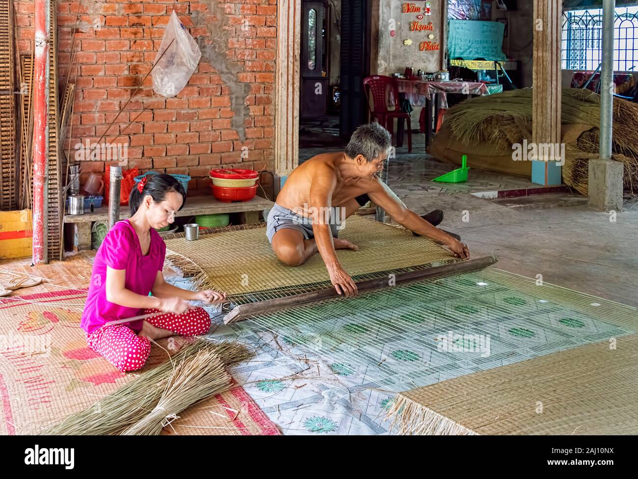 Il vietnamita l uomo e la donna di tessitura tappeti di bambù, ben tre Provincia, Vietnam Foto Stock