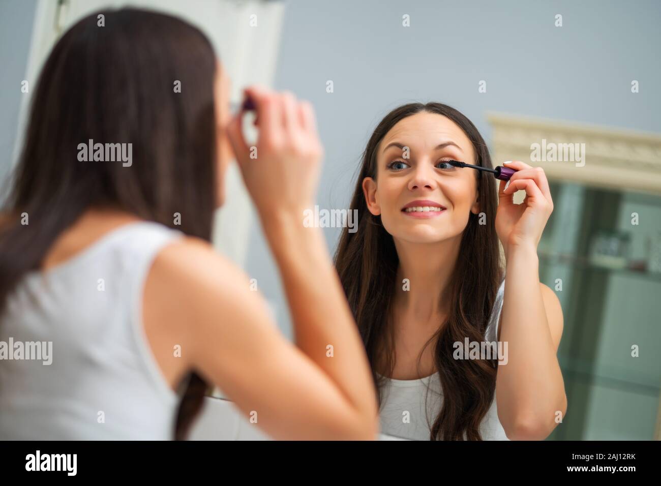 Giovane donna è l'applicazione di mascara in bagno. Foto Stock