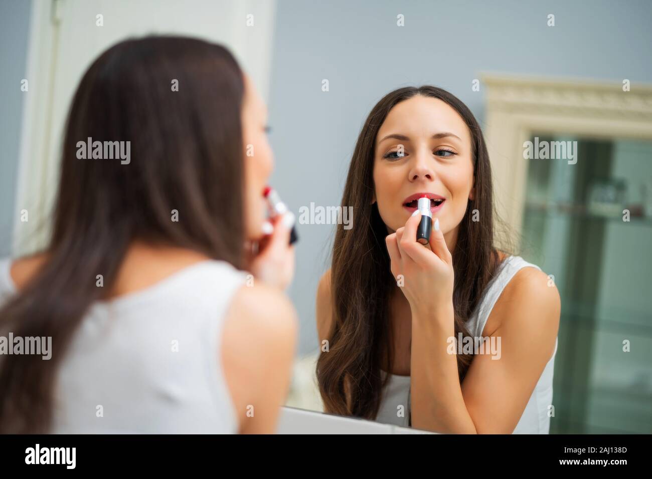 Giovane donna è il rossetto in bagno. Foto Stock