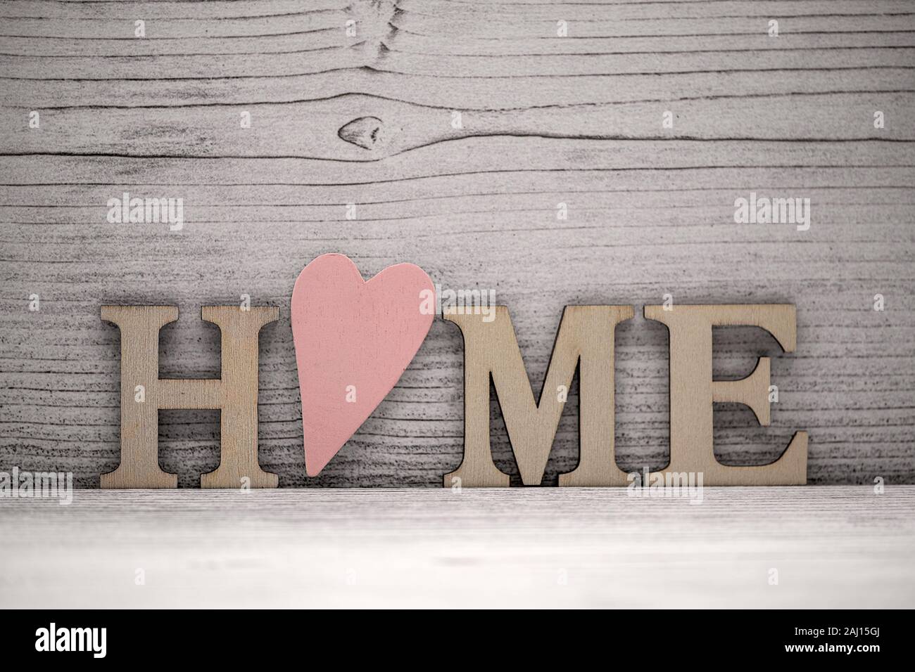 La parola Casa in lettere in legno nella parte anteriore di uno sfondo di legno, o è un legno cuore rosa Foto Stock