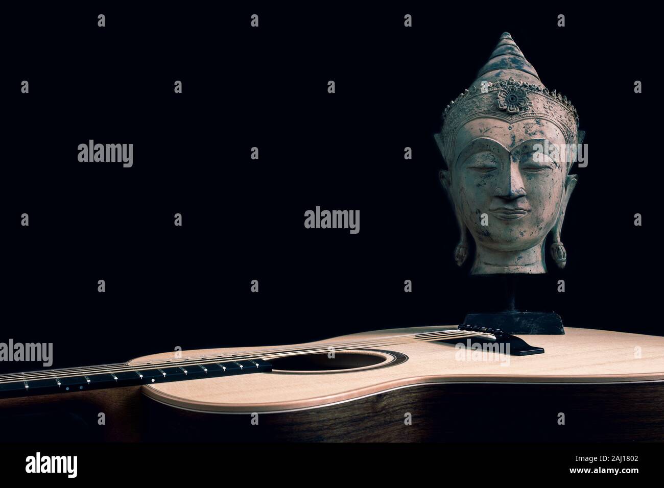 Musica spirituale. Il filosofo musicista. Il cantautore chitarra muse. Tradizionale statua buddista su sfondo nero con copy-spazio. Faccia di Buddha con e Foto Stock