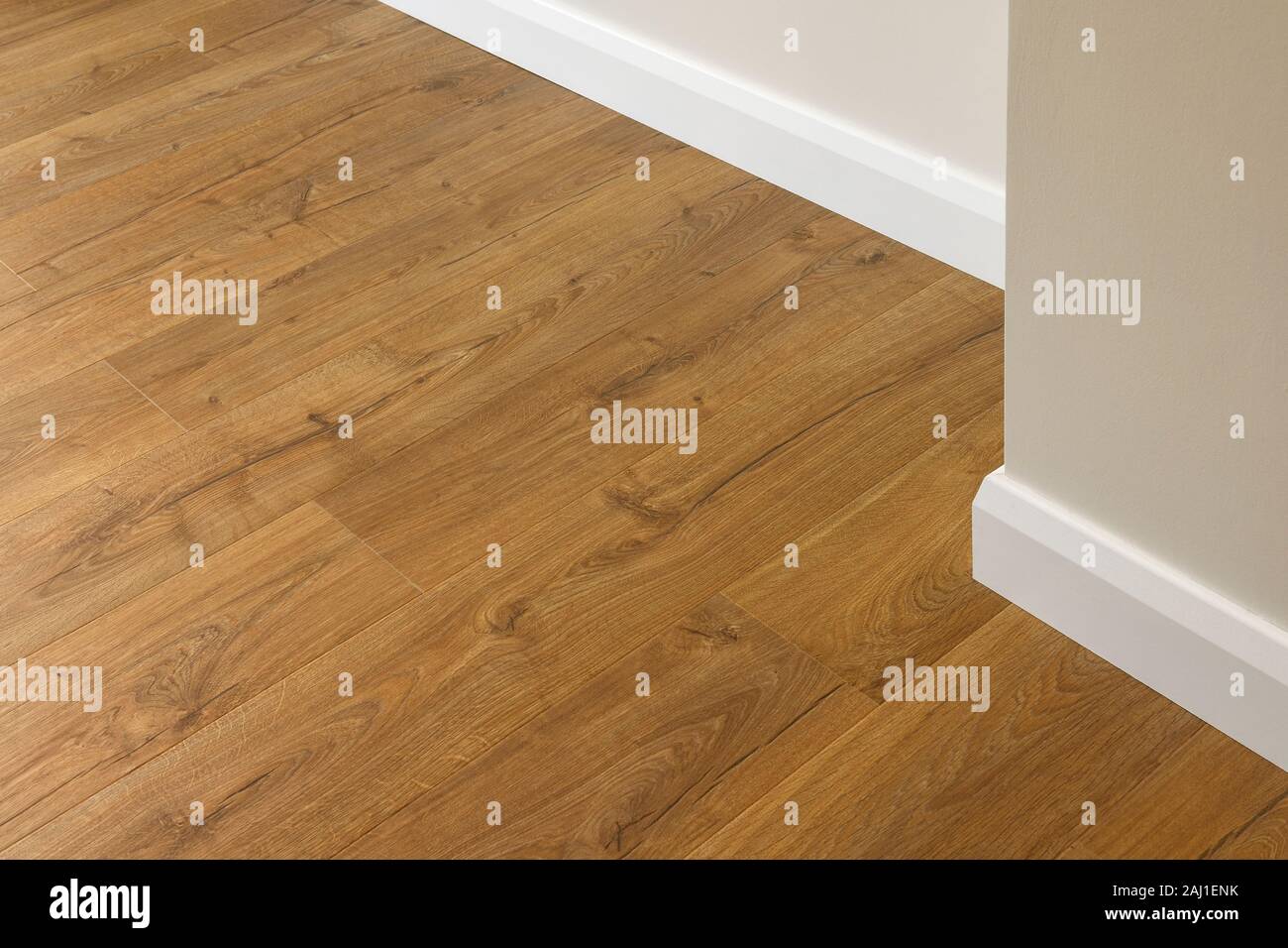 Close up dettaglio di effetto rovere pavimenti in laminato adiacente a una parete e battiscopa Foto Stock