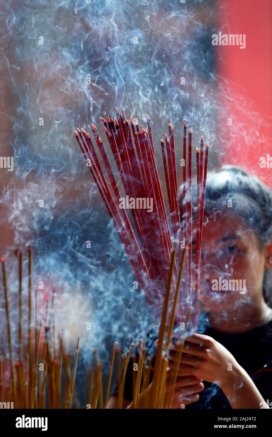 Donna orante con la masterizzazione di bastoncini di incenso, Ongs Bon Pagoda, Tempio Taoista, Ho Chi Minh City, Vietnam, Indocina, Asia sud-orientale, Asia Foto Stock