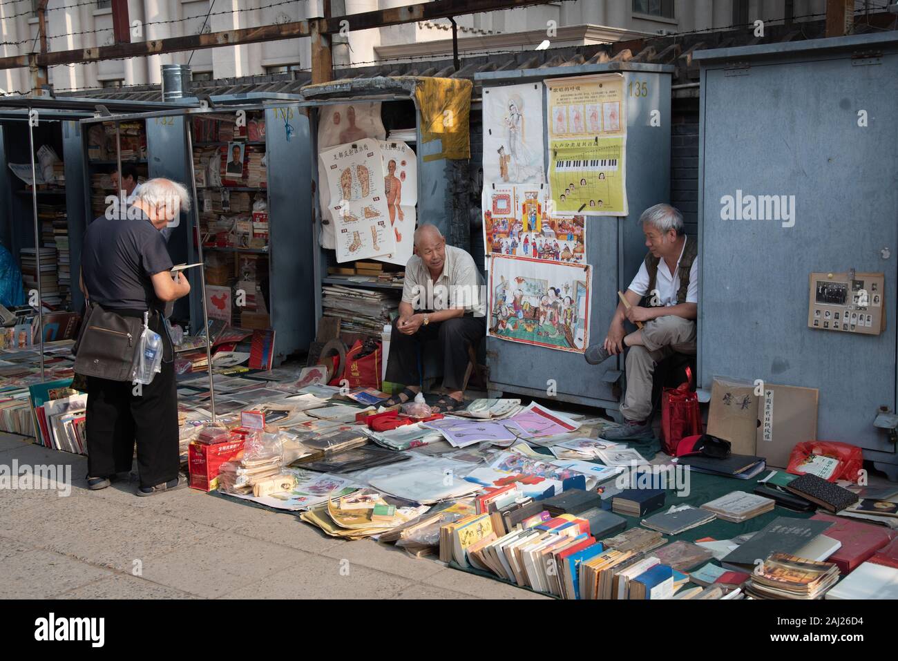 Il cinese uomo asiatico la lettura e la vendita di libri antichi a Panjiayuan pulci Mercato di antiquariato a Beijing in Cina. Foto Stock