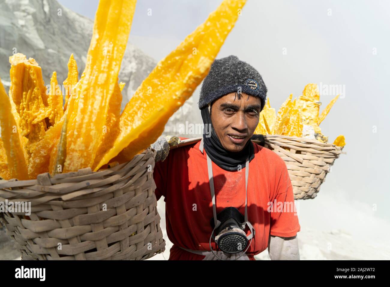 Un minatore trasporta un carico pesante di zolfo navigazione il suo modo fino al cratere del vulcano Ijen.Il vulcano Ijen è uno dei pochi luoghi in cui lo zolfo è ancora minate senza macchine, il cratere di vulcano ha una bocca attiva che produce zolfo elementare. La respirazione nel gas di zolfo può provocare a lungo termine le implicazioni sanitarie ma nonostante ciò non vi è carenza di minatori locali disposti a rischiare tutto per guadagnare un buon stipendio, minatori fare un reddito medio di tre volte superiore al salario locale. Zolfo puro viene utilizzato nella famiglia di prodotti per la pulizia, il make up, esplosivi e purificazione di zucchero. T Foto Stock