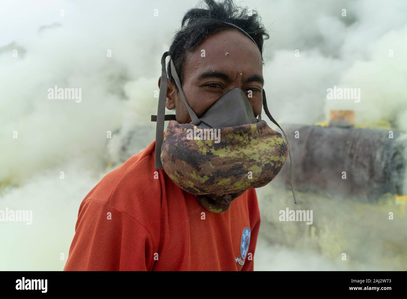 Un minatore mettendo su un gas tossico maschera durante il lavoro presso le miniere di zolfo in profondità all'interno del vulcano Ijen.Il vulcano Ijen è uno dei pochi luoghi in cui lo zolfo è ancora minate senza macchine, il cratere di vulcano ha una bocca attiva che produce zolfo elementare. La respirazione nel gas di zolfo può provocare a lungo termine le implicazioni sanitarie ma nonostante ciò non vi è carenza di minatori locali disposti a rischiare tutto per guadagnare un buon stipendio, minatori fare un reddito medio di tre volte superiore al salario locale. Zolfo puro viene utilizzato nella famiglia di prodotti per la pulizia, il make up, di esplosivi e di purificazione o Foto Stock