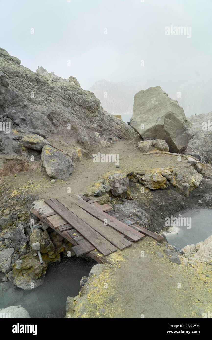 Il fumo di zolfo oscura la visione profondo dentro il vulcano Ijen.Il vulcano Ijen è uno dei pochi luoghi in cui lo zolfo è ancora minate senza macchine, il cratere di vulcano ha una bocca attiva che produce zolfo elementare. La respirazione nel gas di zolfo può provocare a lungo termine le implicazioni sanitarie ma nonostante ciò non vi è carenza di minatori locali disposti a rischiare tutto per guadagnare un buon stipendio, minatori fare un reddito medio di tre volte superiore al salario locale. Zolfo puro viene utilizzato nella famiglia di prodotti per la pulizia, il make up, esplosivi e purificazione di zucchero. Il vulcano attrae anche turiste Foto Stock