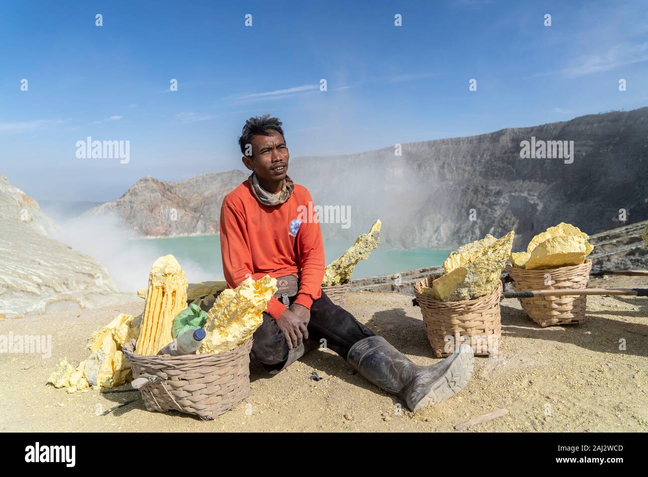 Un Indonesia minatore di zolfo si appoggia al vulcano Ijen.Il vulcano Ijen è uno dei pochi luoghi in cui lo zolfo è ancora minate senza macchine, il cratere di vulcano ha una bocca attiva che produce zolfo elementare. La respirazione nel gas di zolfo può provocare a lungo termine le implicazioni sanitarie ma nonostante ciò non vi è carenza di minatori locali disposti a rischiare tutto per guadagnare un buon stipendio, minatori fare un reddito medio di tre volte superiore al salario locale. Zolfo puro viene utilizzato nella famiglia di prodotti per la pulizia, il make up, esplosivi e purificazione di zucchero. Il vulcano attira anche i turisti che Foto Stock