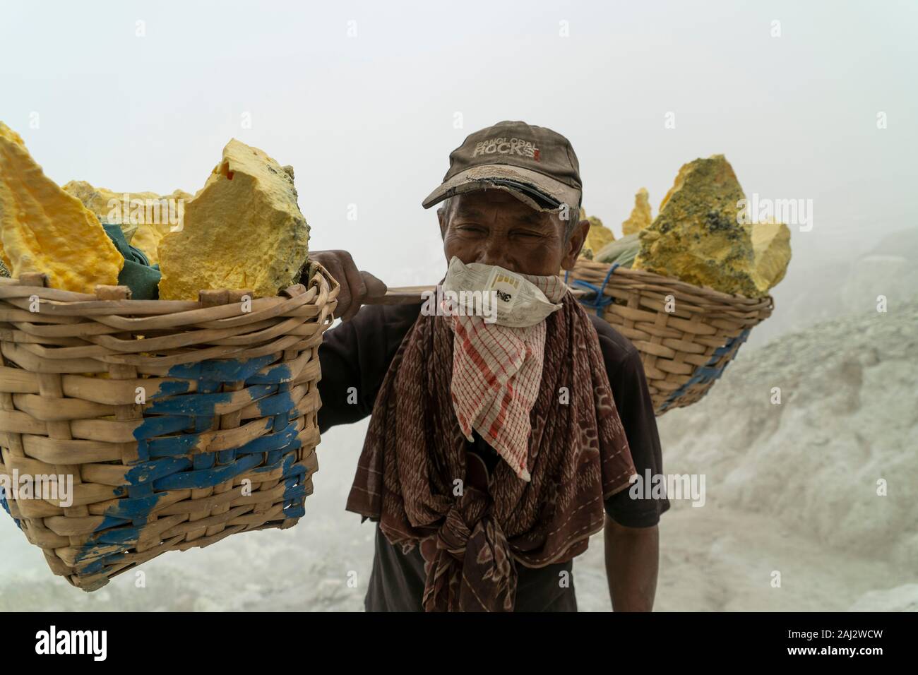 Un minatore trasporta un carico pesante di zolfo navigazione il suo modo fino al cratere del vulcano Ijen.Il vulcano Ijen è uno dei pochi luoghi in cui lo zolfo è ancora minate senza macchine, il cratere di vulcano ha una bocca attiva che produce zolfo elementare. La respirazione nel gas di zolfo può provocare a lungo termine le implicazioni sanitarie ma nonostante ciò non vi è carenza di minatori locali disposti a rischiare tutto per guadagnare un buon stipendio, minatori fare un reddito medio di tre volte superiore al salario locale. Zolfo puro viene utilizzato nella famiglia di prodotti per la pulizia, il make up, esplosivi e purificazione di zucchero. T Foto Stock
