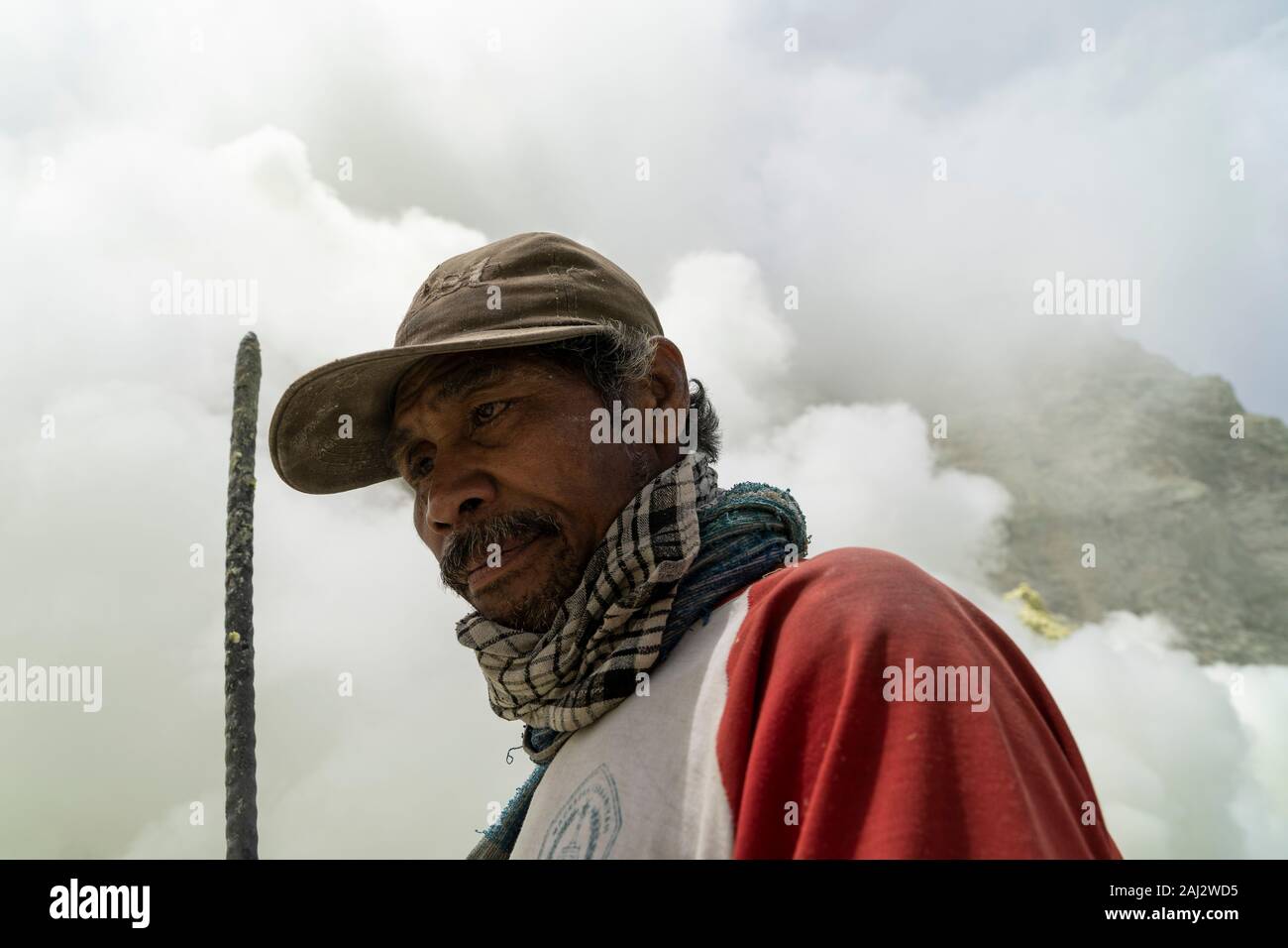 Un minatore indonesiano poggia brevemente dopo una tosse nel vulcano Ijen.Il vulcano Ijen è uno dei pochi luoghi in cui lo zolfo è ancora minate senza macchine, il cratere di vulcano ha una bocca attiva che produce zolfo elementare. La respirazione nel gas di zolfo può provocare a lungo termine le implicazioni sanitarie ma nonostante ciò non vi è carenza di minatori locali disposti a rischiare tutto per guadagnare un buon stipendio, minatori fare un reddito medio di tre volte superiore al salario locale. Zolfo puro viene utilizzato nella famiglia di prodotti per la pulizia, il make up, esplosivi e purificazione di zucchero. Il vulcano anche Foto Stock