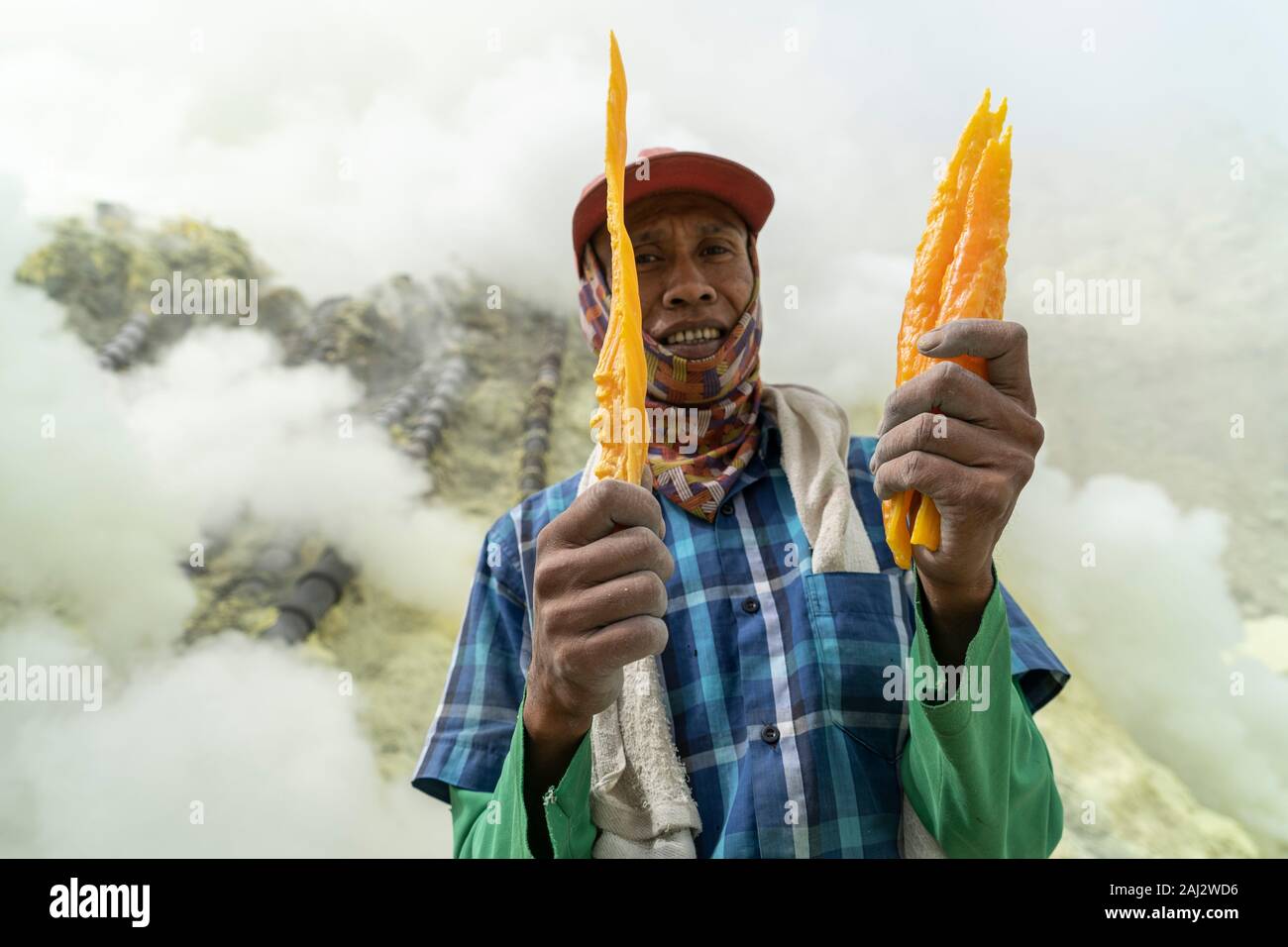 Un indonesiano minatore di zolfo si mette in mostra alcuni dei materiali ha estratto dalla terra nel vulcano Ijen.Il vulcano Ijen è uno dei pochi luoghi in cui lo zolfo è ancora minate senza macchine, il cratere di vulcano ha una bocca attiva che produce zolfo elementare. La respirazione nel gas di zolfo può provocare a lungo termine le implicazioni sanitarie ma nonostante ciò non vi è carenza di minatori locali disposti a rischiare tutto per guadagnare un buon stipendio, minatori fare un reddito medio di tre volte superiore al salario locale. Zolfo puro viene utilizzato nella famiglia di prodotti per la pulizia, il make up, esplosivi e purific Foto Stock