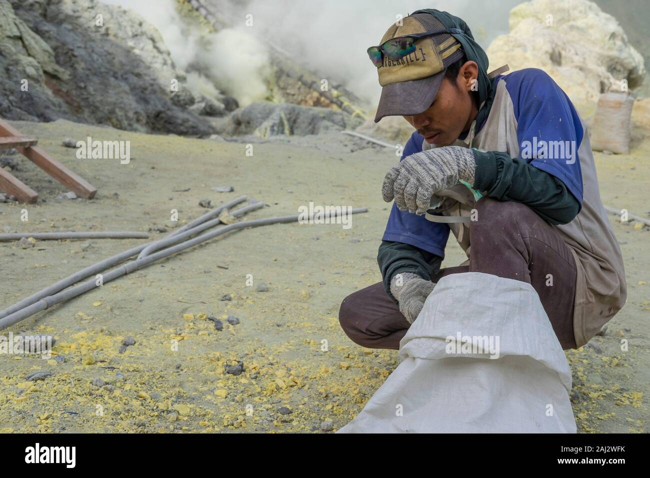 Un indonesiano minatore di zolfo funziona profondo dentro il cratere del vulcano Ijen.Il vulcano Ijen è uno dei pochi luoghi in cui lo zolfo è ancora minate senza macchine, il cratere di vulcano ha una bocca attiva che produce zolfo elementare. La respirazione nel gas di zolfo può provocare a lungo termine le implicazioni sanitarie ma nonostante ciò non vi è carenza di minatori locali disposti a rischiare tutto per guadagnare un buon stipendio, minatori fare un reddito medio di tre volte superiore al salario locale. Zolfo puro viene utilizzato nella famiglia di prodotti per la pulizia, il make up, esplosivi e purificazione di zucchero. Il vulcano al Foto Stock