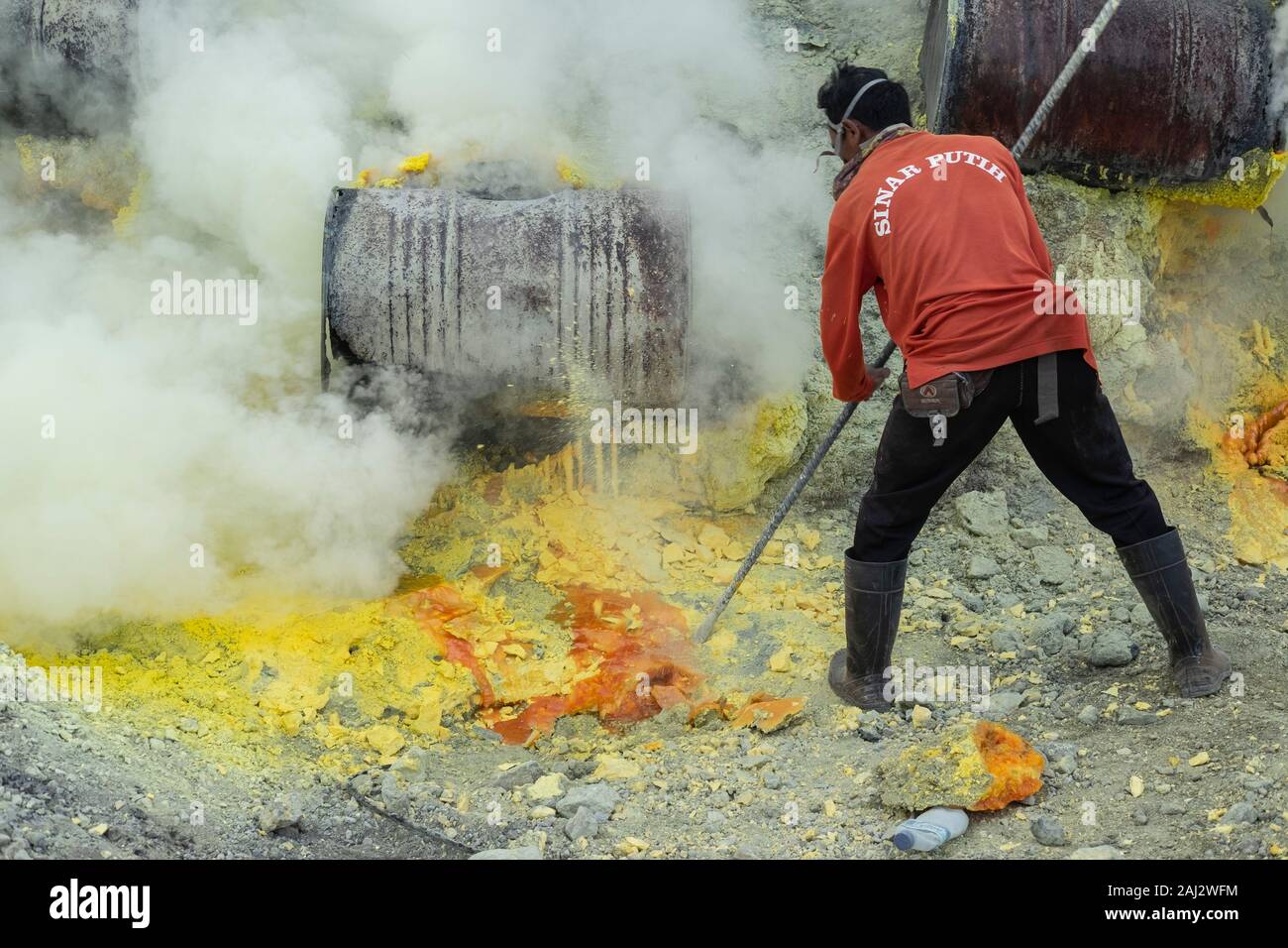 Un indonesiano minatore di zolfo funziona profondo dentro il cratere del vulcano Ijen.Il vulcano Ijen è uno dei pochi luoghi in cui lo zolfo è ancora minate senza macchine, il cratere di vulcano ha una bocca attiva che produce zolfo elementare. La respirazione nel gas di zolfo può provocare a lungo termine le implicazioni sanitarie ma nonostante ciò non vi è carenza di minatori locali disposti a rischiare tutto per guadagnare un buon stipendio, minatori fare un reddito medio di tre volte superiore al salario locale. Zolfo puro viene utilizzato nella famiglia di prodotti per la pulizia, il make up, esplosivi e purificazione di zucchero. Il vulcano al Foto Stock