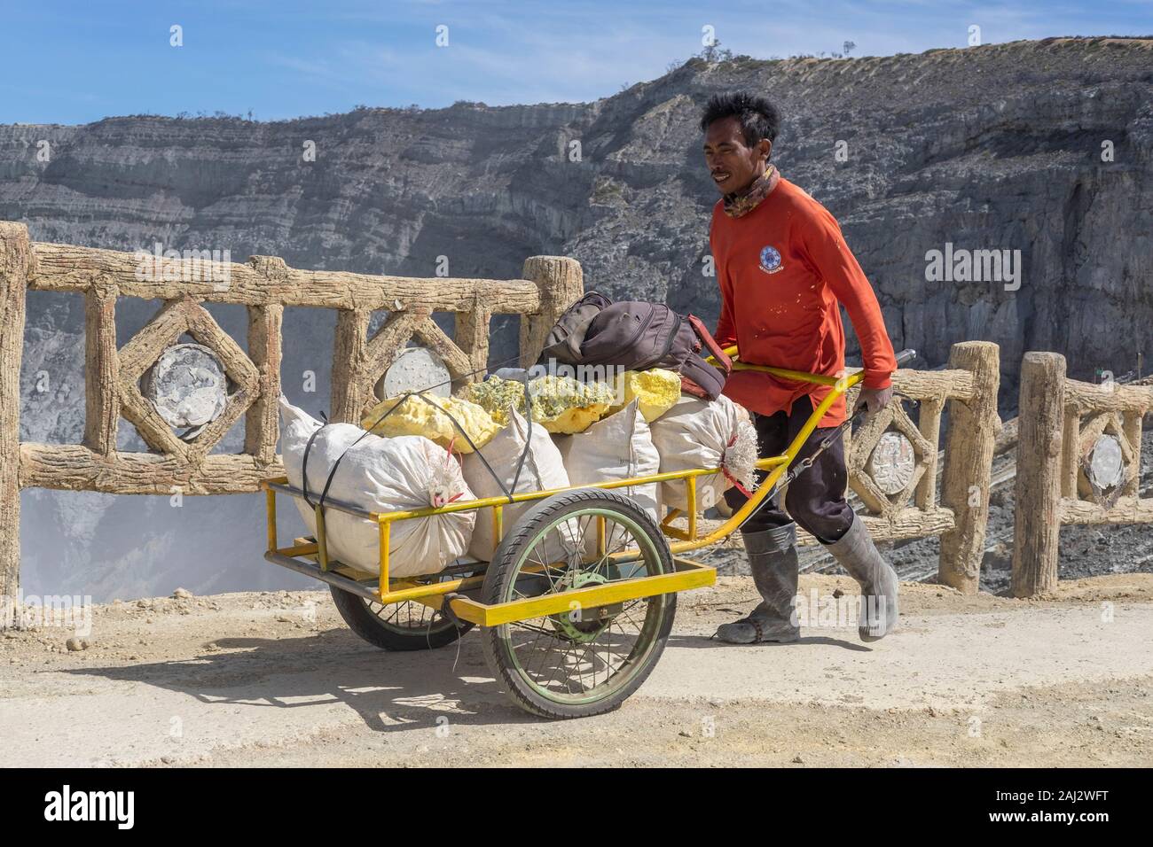 Un Indonesia miner si serve di un carrello per trasportare il suo carico di zolfo giù il vulcano Ijen.Il vulcano Ijen è uno dei pochi luoghi in cui lo zolfo è ancora minate senza macchine, il cratere di vulcano ha una bocca attiva che produce zolfo elementare. La respirazione nel gas di zolfo può provocare a lungo termine le implicazioni sanitarie ma nonostante ciò non vi è carenza di minatori locali disposti a rischiare tutto per guadagnare un buon stipendio, minatori fare un reddito medio di tre volte superiore al salario locale. Zolfo puro viene utilizzato nella famiglia di prodotti per la pulizia, il make up, esplosivi e purificazione di zucchero. Il v Foto Stock