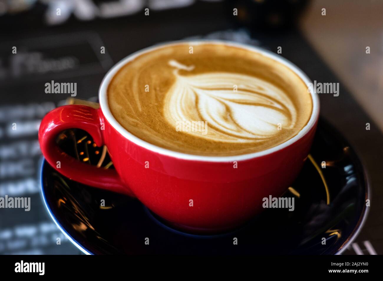 Caffe latte macchiato cappuccino in rosso mug in casa cafe con schiuma di latte art Foto Stock
