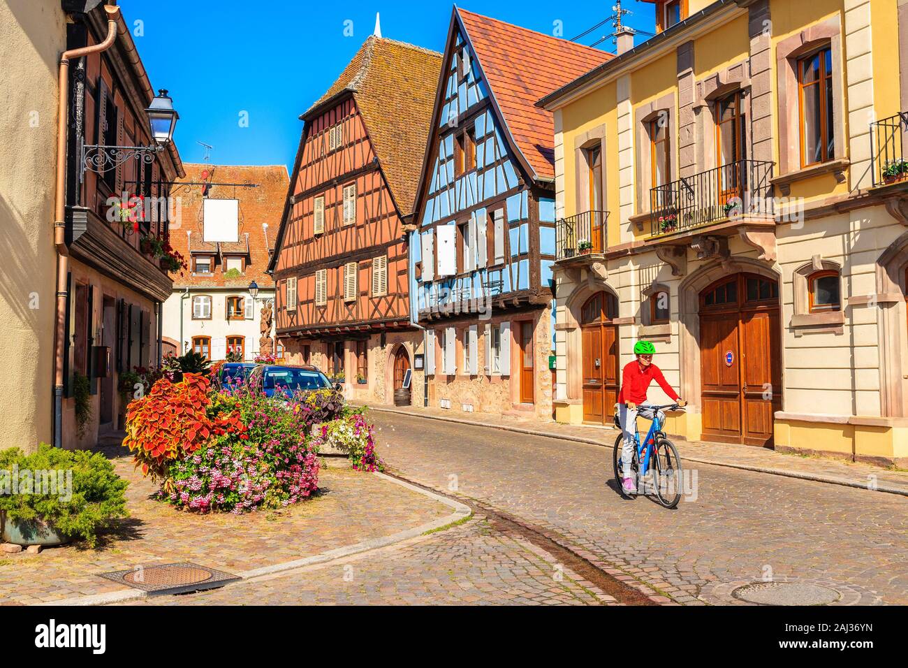 Donna cicloturismo su strada nel bellissimo villaggio antico di Kintzheim  che si trova sulla famosa strada dei vini di Alsazia, Francia Foto stock -  Alamy