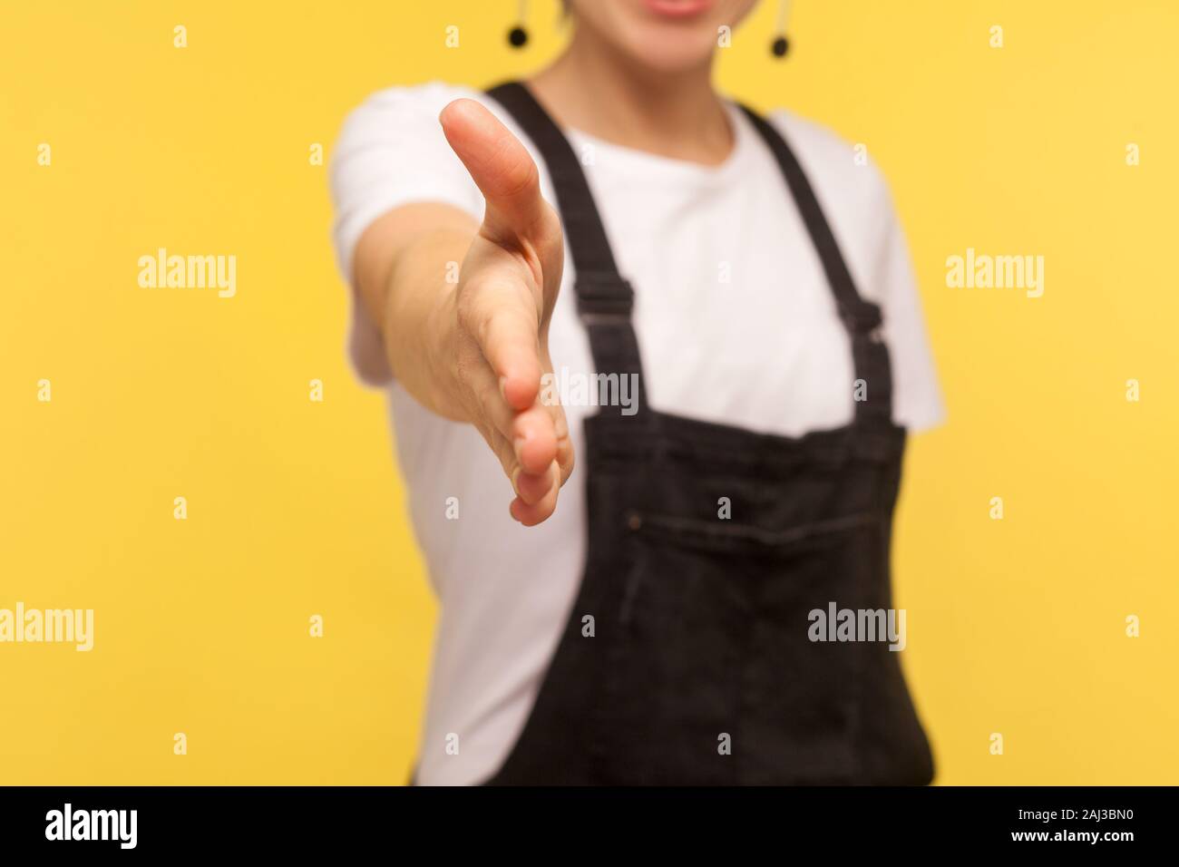 Primo piano della lavoratrice in tuta outstretching braccio alla fotocamera, dando la mano per stretta di mano, job ricorrente conoscere su intervista, ospitale Foto Stock