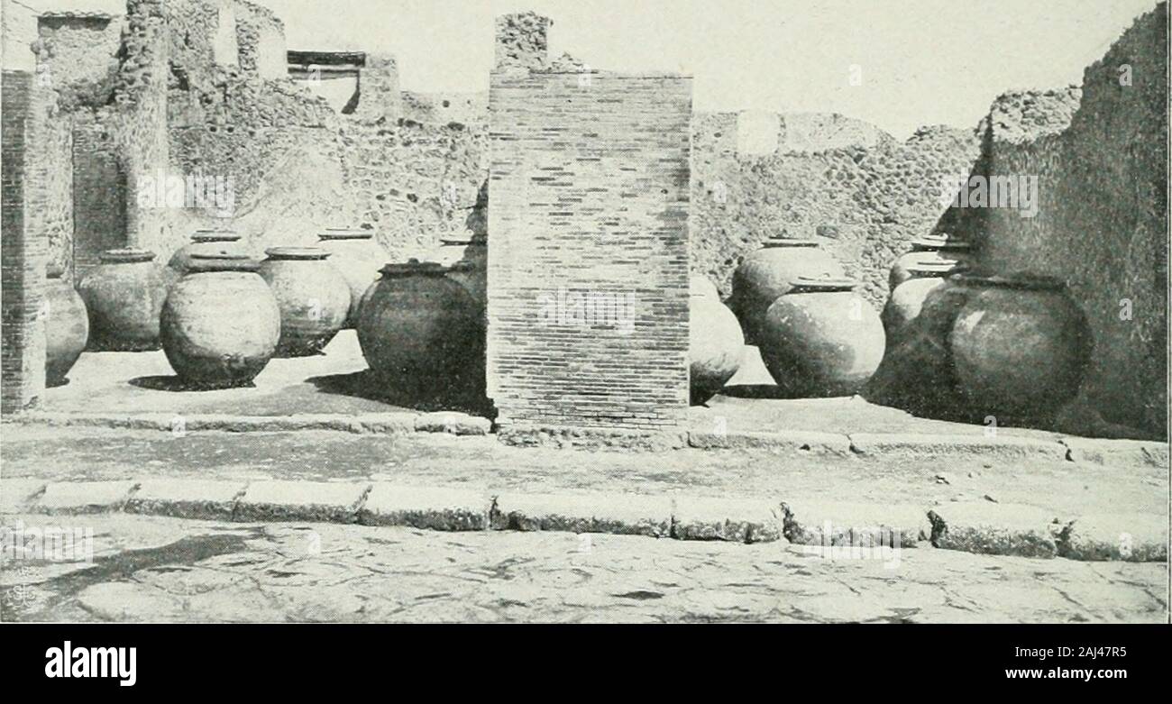 Pompéi : vie publique . Fig. 6j. - Doliams de marchands dhuile et autres denrées (p. 123). tique, il savon naturel, avec laquelle les étoffes étaient nettoyées ; su seservait aussi, pour cet usage, durine ou de potasse. La foulerie quenous représentons ici iig. 66, p. 123; est celle de la rue de Stabies;cest une maison particulière transformée en foulerie. Après avoir traverséson joli atrium qui a conservé, dans limpluvium, la vasque, la base dela statua-fontaine et le cartibulum, su rencontre Au delà du tablinum, aulieu du Jardin, les longues cuves et les endroits où su foulait. Sur le mur degau Foto Stock