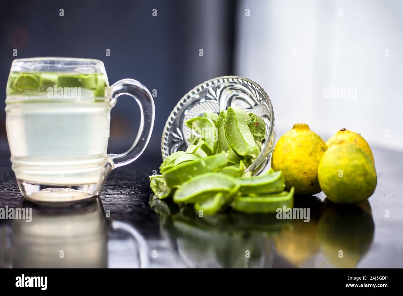 In prossimità della tazza di vetro su una superficie di legno contenenti aloe vera e il succo di limone detox bere insieme con il suo intero ingredienti grezzi con esso. Sho orizzontale Foto Stock