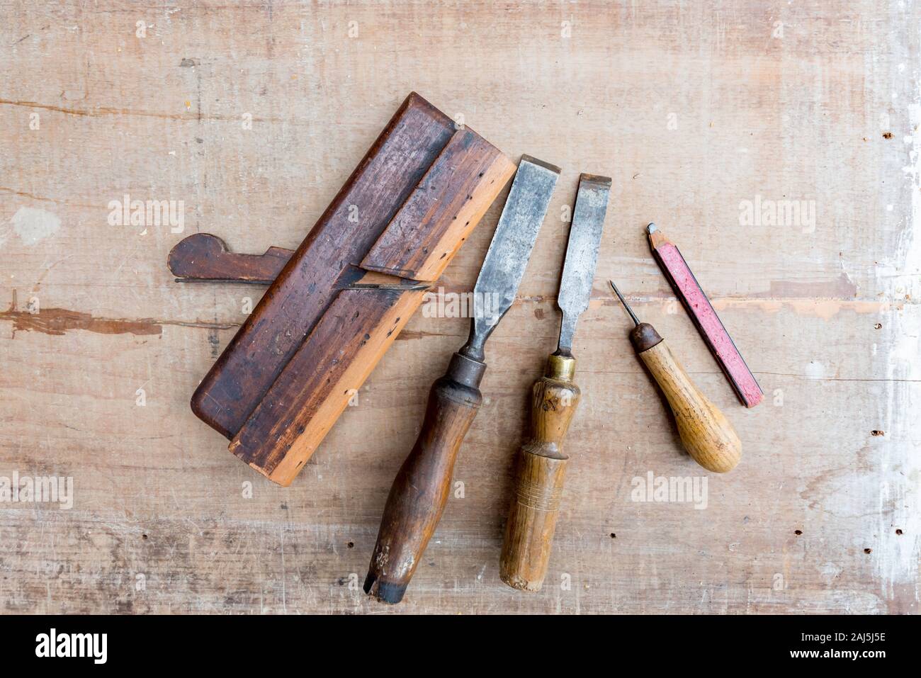 Vecchio scalpelli e altri utensili a mano che giace piatto su una superficie ruvida pezzo di legname con contrassegni di vernice e graffi Foto Stock