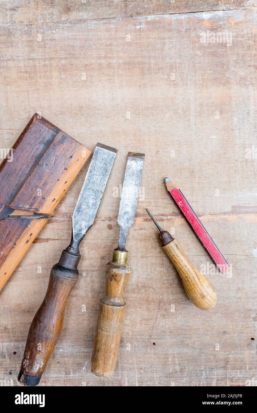 Vecchio scalpelli e altri utensili a mano che giace piatto su una superficie ruvida pezzo di legname con contrassegni di vernice e graffi Foto Stock