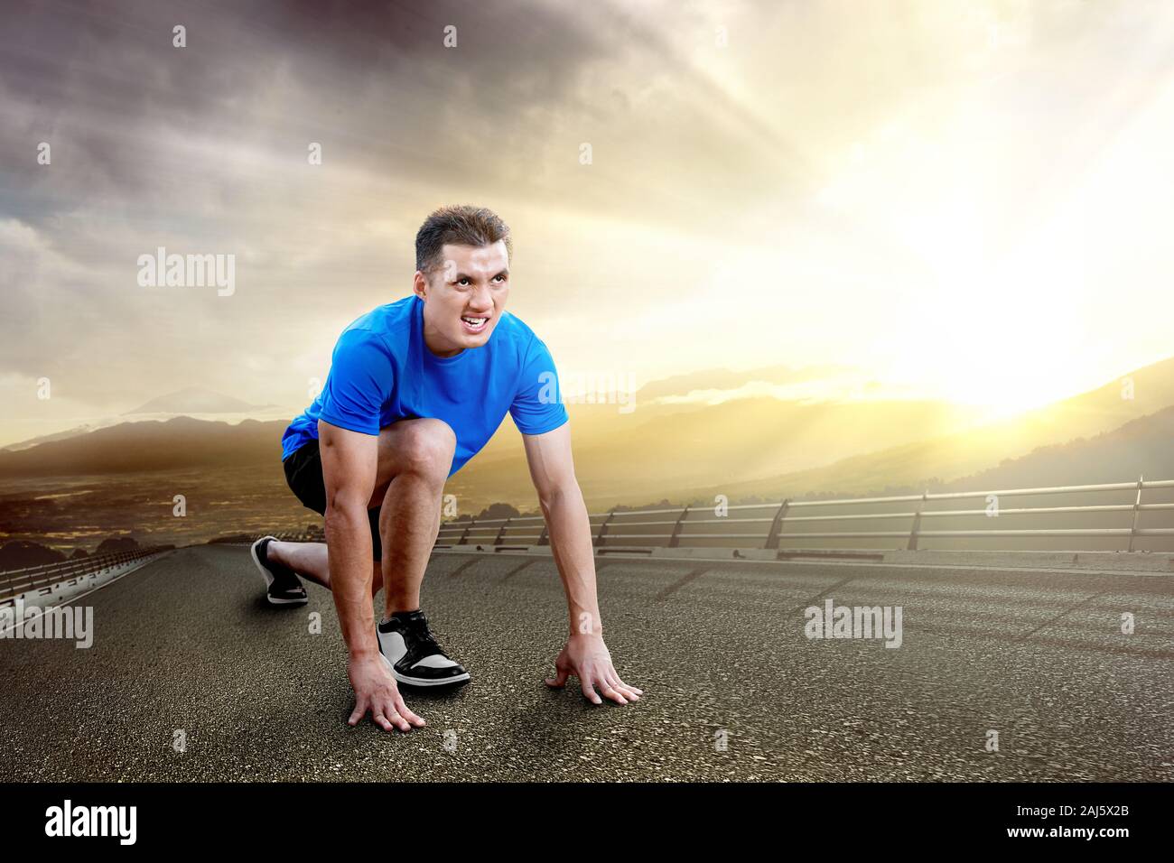 Asian runner uomo pronto a correre per la strada con la luce del sole sullo sfondo Foto Stock